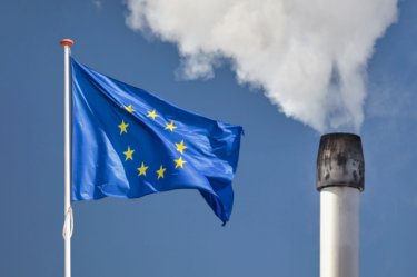 Europaflagge vor einem Fabriksschornstein